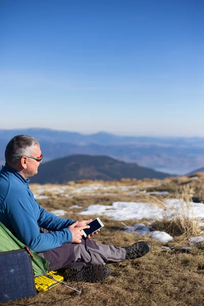 Die Solarzelle, die am Zelt befestigt ist. Der Mann sitzt neben Handyladungen von der Sonne. — Stockfoto