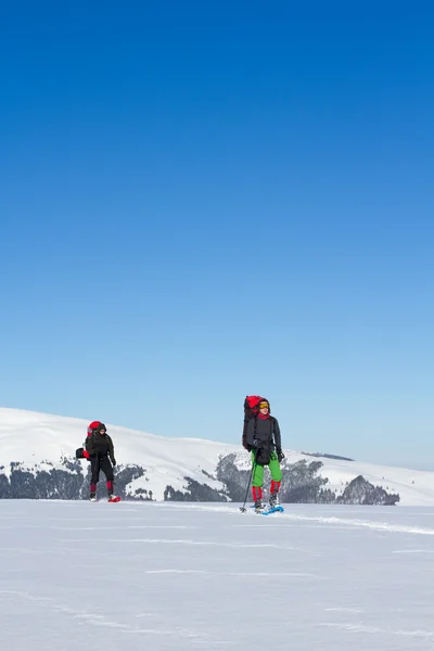 Caminhadas de inverno nas montanhas em sapatos de neve com uma mochila e tenda . — Fotografia de Stock