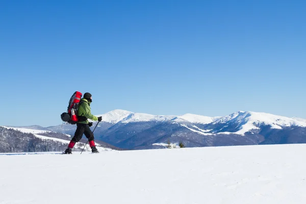 Téli túrázás a hegyekben a hótalp hátizsák és sátor. — Stock Fotó