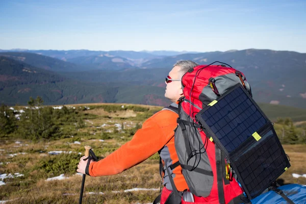 The solar panel attached to the tent. The man sitting next to mobile phone charges from the sun. — Stock Photo, Image