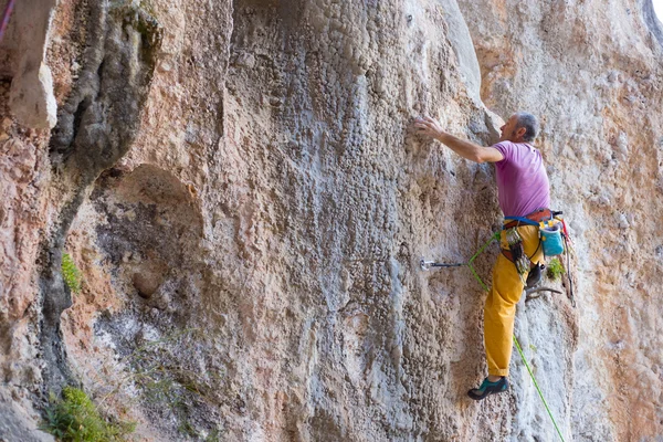 Rock klimmer klimt op een rotsachtige muur. — Stockfoto