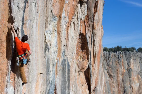 Rock klimmer klimt op een rotsachtige muur. — Stockfoto
