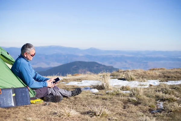 El panel solar unido a la carpa. El hombre sentado al lado del teléfono móvil carga desde el sol . —  Fotos de Stock