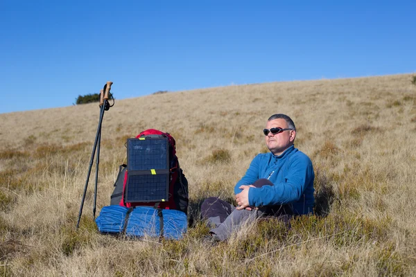 Le panneau solaire fixé à la tente. L'homme assis à côté des frais de téléphone portable du soleil . — Photo