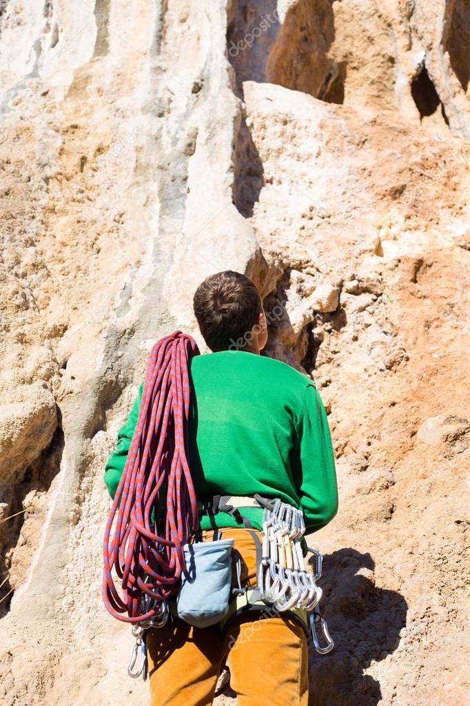 Young male climber hanging by a cliff.