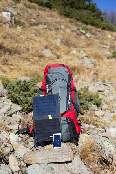 Die Solarzelle, die am Zelt befestigt ist. Der Mann sitzt neben Handyladungen von der Sonne. — Stockfoto