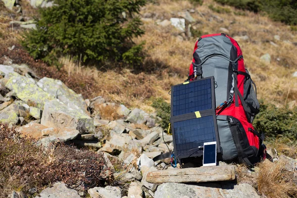 Die Solarzelle, die am Zelt befestigt ist. Der Mann sitzt neben Handyladungen von der Sonne. — Stockfoto