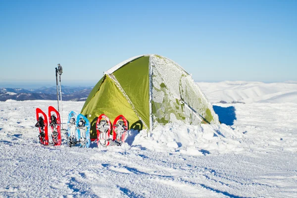 Tenda montanhas de inverno.Tenda fica nas montanhas na neve. Sapatilhas de neve ao lado da tenda . — Fotografia de Stock