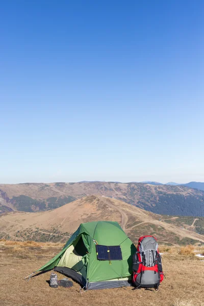 The solar panel attached to the tent. The man sitting next to mobile phone charges from the sun. — Stock Photo, Image