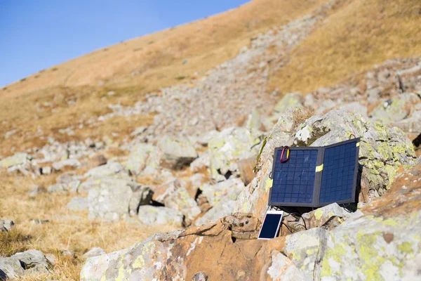 Solpanelen kopplad till tältet. Mannen sitter bredvid mobiltelefon avgifter från solen. — Stockfoto