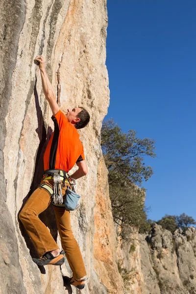 Junger männlicher Kletterer hängt an einer Klippe. — Stockfoto