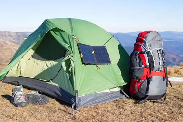 Il pannello solare attaccato alla tenda. L'uomo seduto accanto al cellulare carica dal sole . — Foto Stock