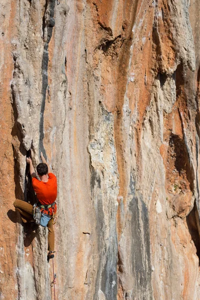 Joven escalando en una pared de piedra caliza con amplio valle en el fondo — Foto de Stock