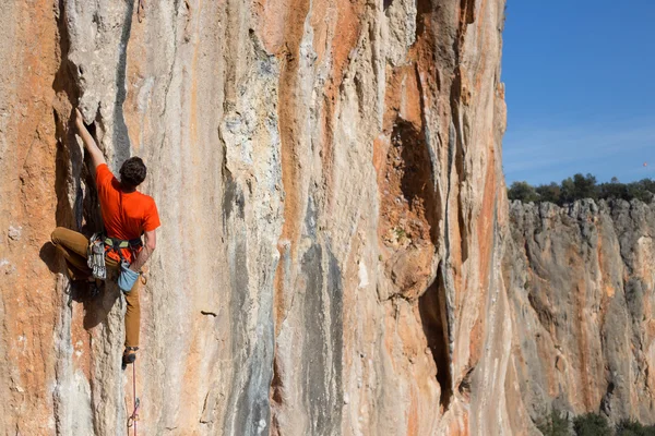 Fiatalember mászik a mészkő falán széles völgy a háttérben — Stock Fotó