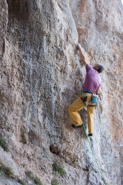 Joven escalando en una pared de piedra caliza con amplio valle en el fondo —  Fotos de Stock