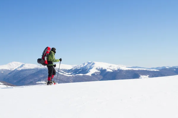 Winter wandelen in de bergen op sneeuwschoenen met een rugzak en tent. — Stockfoto