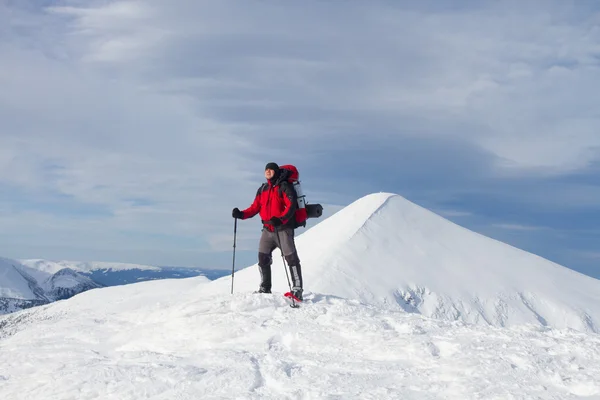 Caminhadas de inverno nas montanhas em sapatos de neve com uma mochila e tenda . — Fotografia de Stock