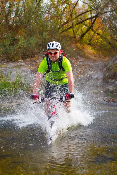 Jeune athlète traversant un terrain rocheux à vélo dans ses mains . — Photo