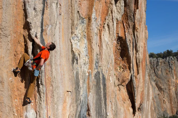 Fiatal férfi mászó lóg egy sziklán. — Stock Fotó
