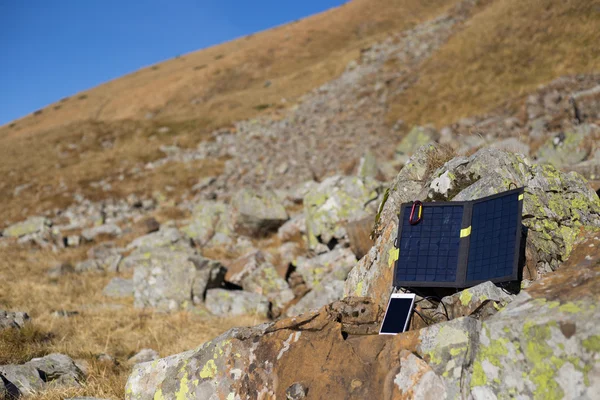 The solar panel attached to the tent. The man sitting next to mobile phone charges from the sun. — Stock Photo, Image