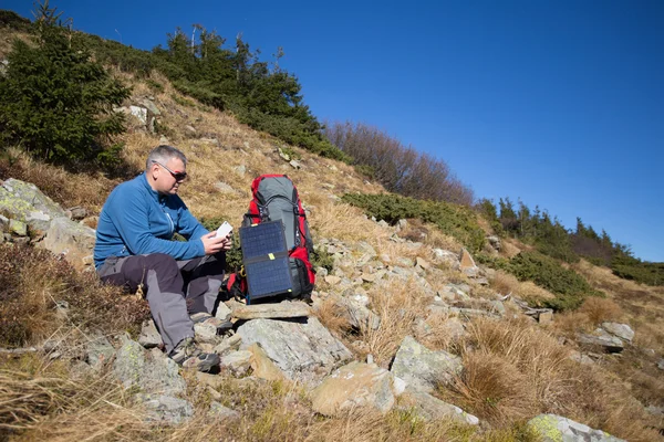 Il pannello solare attaccato alla tenda. L'uomo seduto accanto al cellulare carica dal sole . — Foto Stock