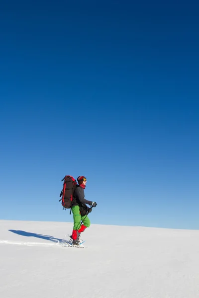 Caminhadas de inverno nas montanhas em sapatos de neve com uma mochila e tenda . — Fotografia de Stock