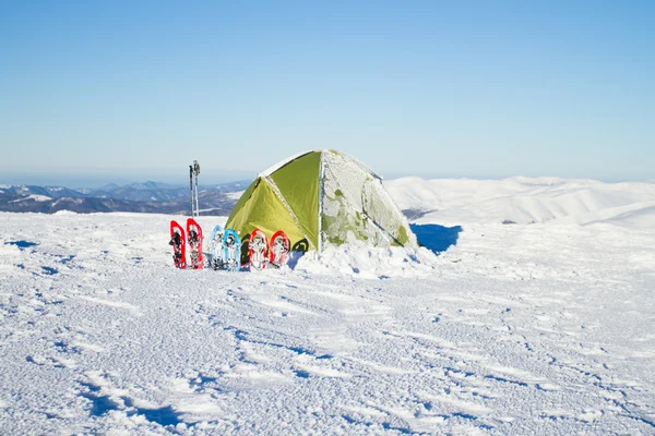 Sátor téli hegyek. Sátor áll, a hó a hegyekben. Hótalpakat állnak a sátor mellett. — Stock Fotó