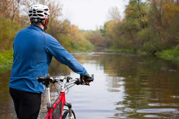 Young athlete crossing rocky terrain with bicycle in his hands. — Stock Photo, Image