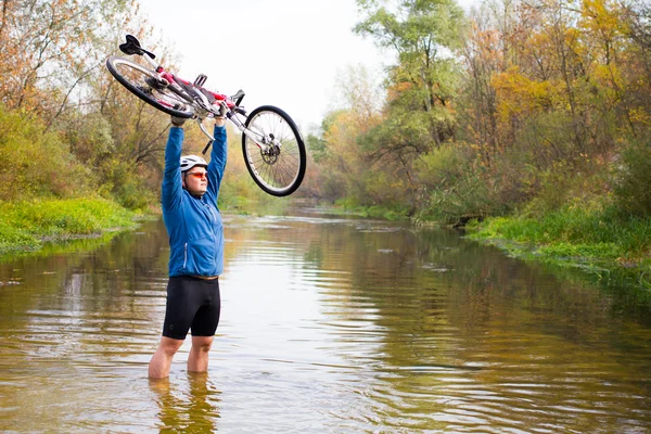 Young athlete crossing rocky terrain with bicycle in his hands. — Stock Photo, Image