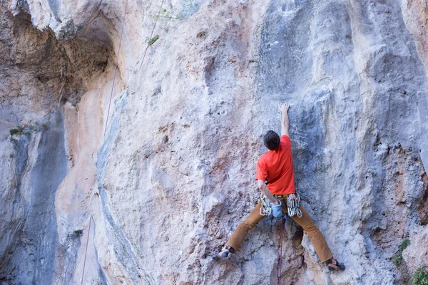 Fiatal férfi mászó lóg egy sziklán. — Stock Fotó