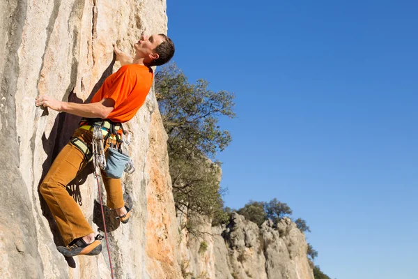 崖にぶら下がっている若い男性登山家. — ストック写真