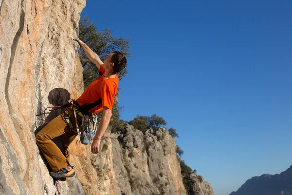 Jonge mannelijke bergbeklimmer op uitdagende route op klif — Stockfoto