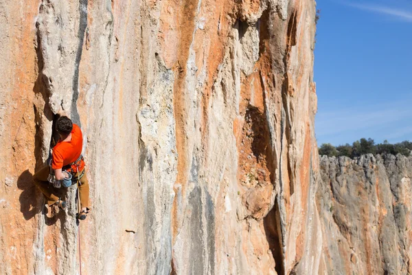 Jongeman klimmend op een kalkstenen muur met brede vallei op de achtergrond — Stockfoto