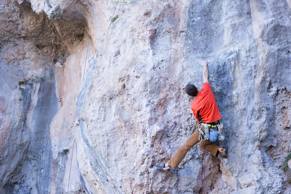 Junger Mann klettert an einer Kalksteinwand mit breitem Tal im Hintergrund — Stockfoto