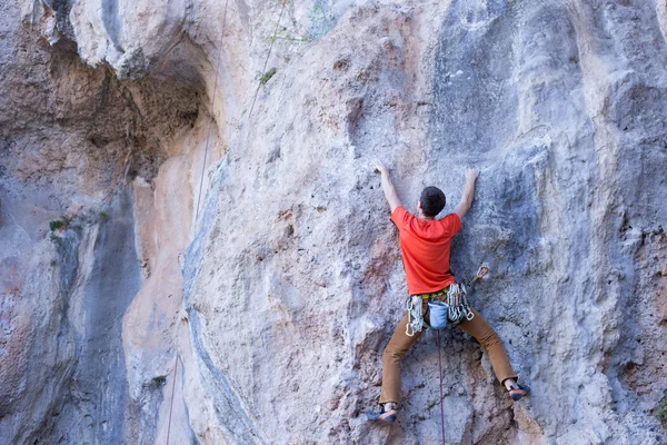 Joven escalando en una pared de piedra caliza con amplio valle en el fondo — Foto de Stock