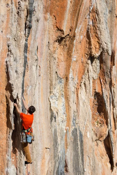 Joven escalando en una pared de piedra caliza con amplio valle en el fondo — Foto de Stock
