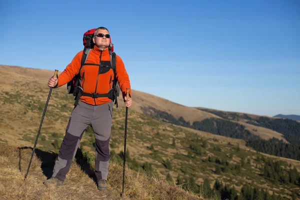 Man hiking in the mountains with a backpack and tent. — Stock Photo, Image