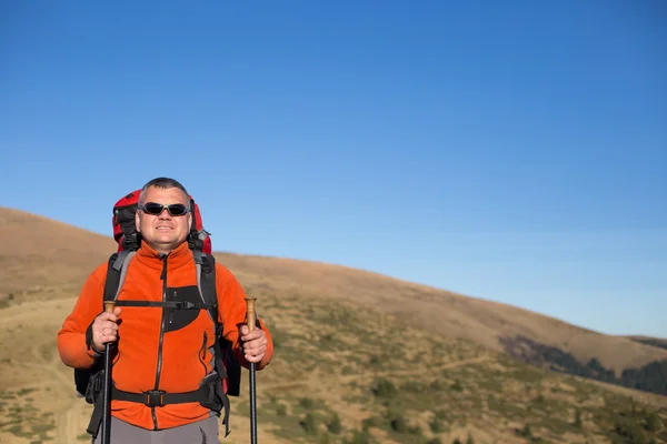 Man wandelen in de bergen met een rugzak en tent. — Stockfoto