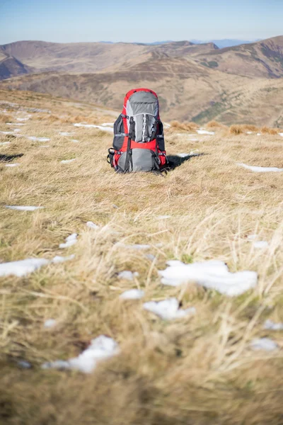 Κόκκινο σακίδιο στέκεται στην κορυφή του βουνού. — Φωτογραφία Αρχείου