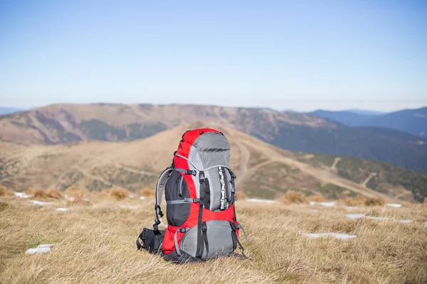 Röd ryggsäck stående på toppen av berget. — Stockfoto