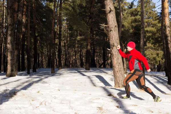 Winter trail uitgevoerd: man neemt een run op een besneeuwde bergpad in een pine woods. — Stockfoto