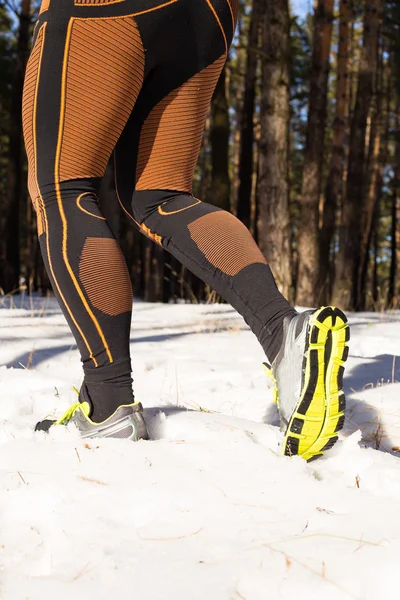 Winter trail uitgevoerd: man neemt een run op een besneeuwde bergpad in een pine woods. — Stockfoto