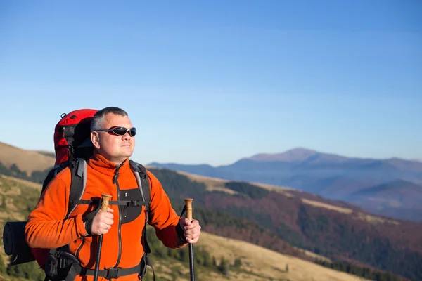 Man wandelen in de bergen met een rugzak en tent. — Stockfoto