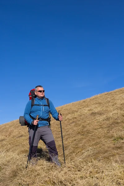 Man wandelen in de bergen met een rugzak en tent. — Stockfoto