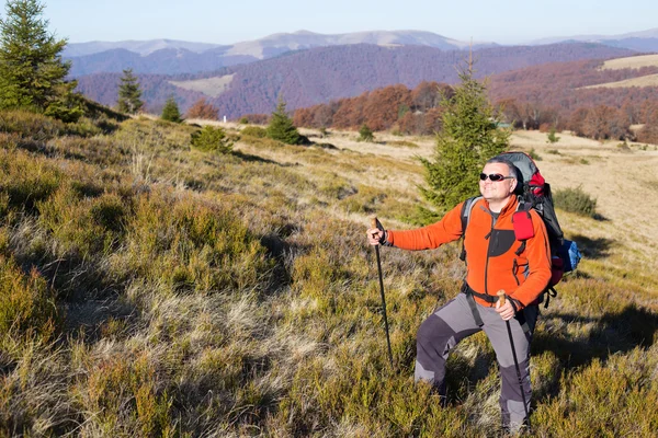 Man wandelen in de bergen met een rugzak en tent. — Stockfoto