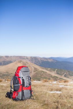 Kırmızı sırt çantası ayakta dağın zirvesinde.