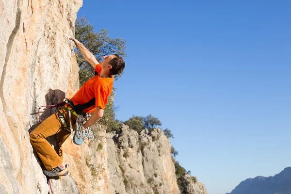 Junger männlicher Kletterer hängt an einer Klippe. — Stockfoto