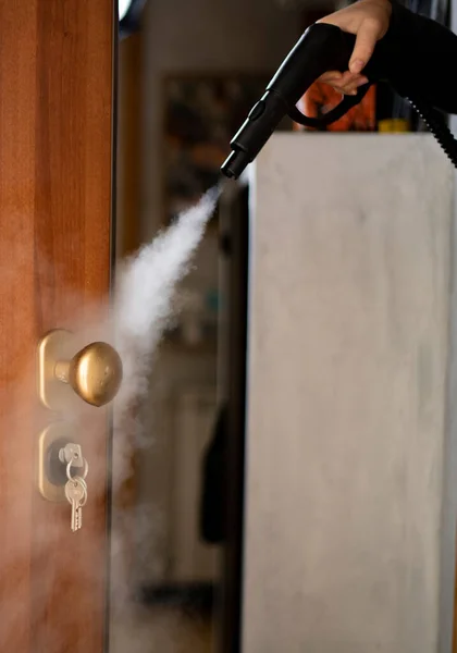 disinfection and sanitization with steam at home, steam flow is directed to the door handle and keys in the lock