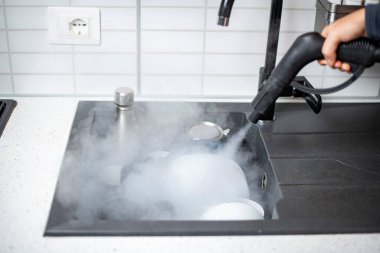 Evin dezenfeksiyon ve dezenfekte edilmesi, mutfak lavabosundaki buharlı bulaşıklar.