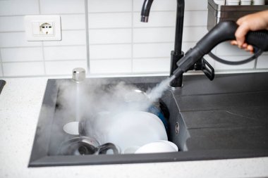 Evin dezenfeksiyon ve dezenfekte edilmesi, mutfak lavabosundaki buharlı bulaşıklar.